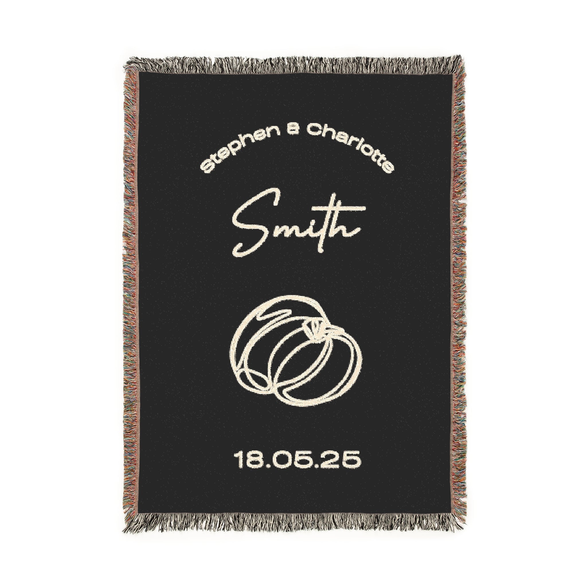 A black custom woven blanket that is accented with vibrant, multicolored fringe along the two side edges and a contrasting classic black-and-white fringe along the top and bottom edges. The design includes the names [First Names] and [Last Name], rings, and the date [Date] in beige text.