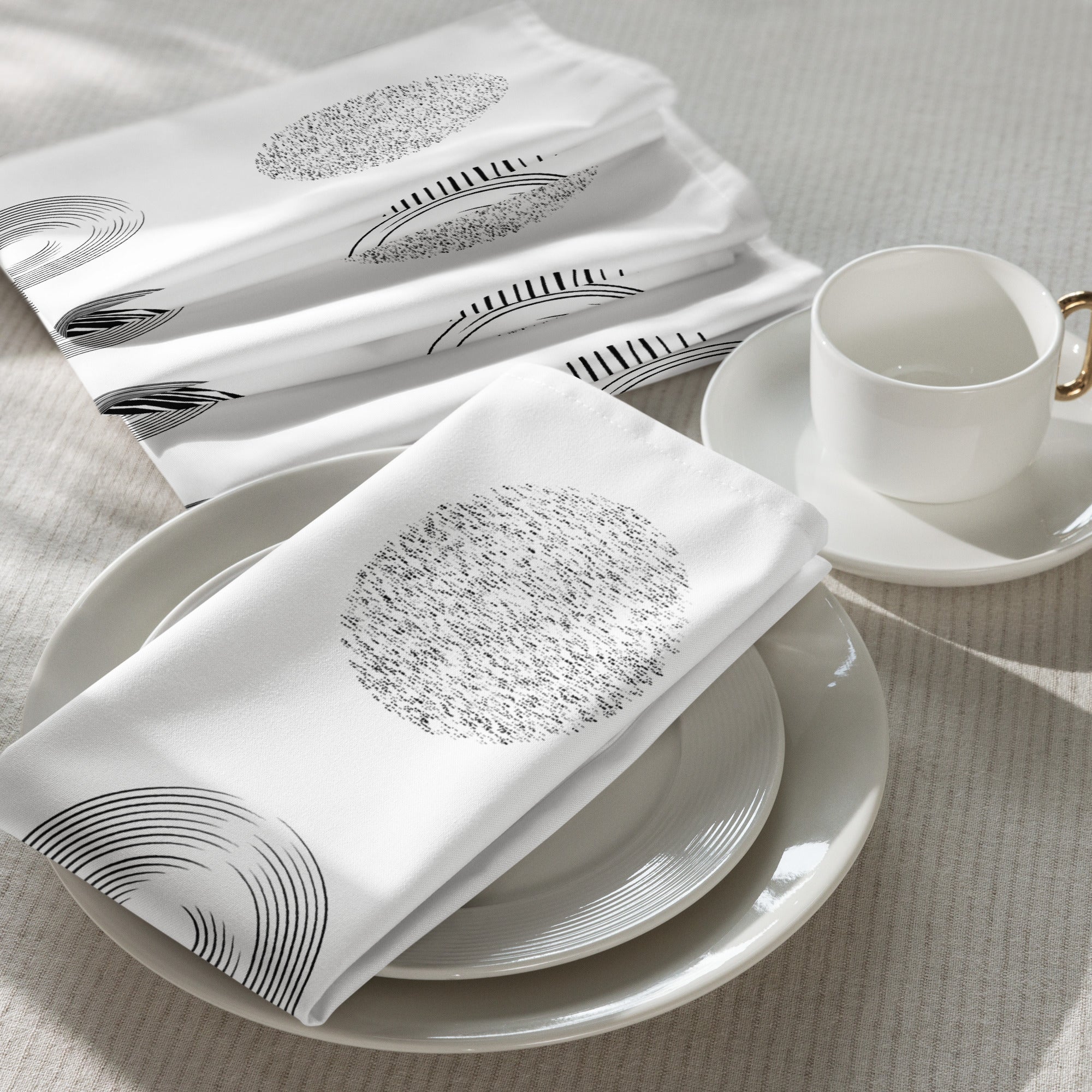 Set of four white cotton napkins featuring a modern nine-circle pattern, styled on a dining table with a cup and plates.