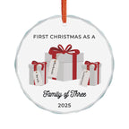 Round, crystal glass Christmas ornament. It features a vivid illustration of a stack of colorful wrapped presents, each secured with a ribbon. The names of family members are personalised and printed on a label in the front of each gift box. The main commemorative text, 'First Christmas as a Family of Three' and the year (e.g., 2025), is centered at the bottom of the ornament.