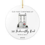 Round ceramic Christmas ornament featuring a house illustration and the text "Our First Christmas at" followed by a personalised address, names, and the year.