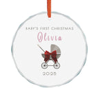 Round crystal glass Christmas ornament featuring a baby carriage (pram) design accented with a red bow. Personalised text includes the baby's name, the year, and the phrase "Baby's First Christmas". 