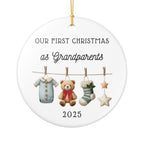 Decorative ceramic Christmas ornament with text 'Our First Christmas as Grandparents 2025'. Featuring a teddy bear, baby clothes, and stars.