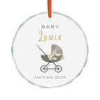 Round crystal glass Christmas ornament featuring a baby carriage (pram) design accented with small flowers. Personalised text includes the baby's name, the year, and the phrases "Baby" and "Arriving."