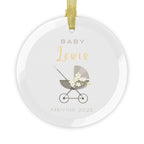 Round glass Christmas ornament featuring a baby carriage (pram) design accented with small flowers. Personalised text includes the baby's name, the year, and the phrases "Baby" and "Arriving."