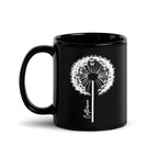 Black glossy ceramic mug with a delicate white dandelion design and a custom name printed on the front. 11oz personalised coffee cup, ideal for tea, coffee, or hot chocolate lovers.
