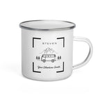 A white 12-ounce metal camping mug featuring a vintage camper van design with mountains in the background and a customizable name above the illustration, with a L shaped frame on each corner.