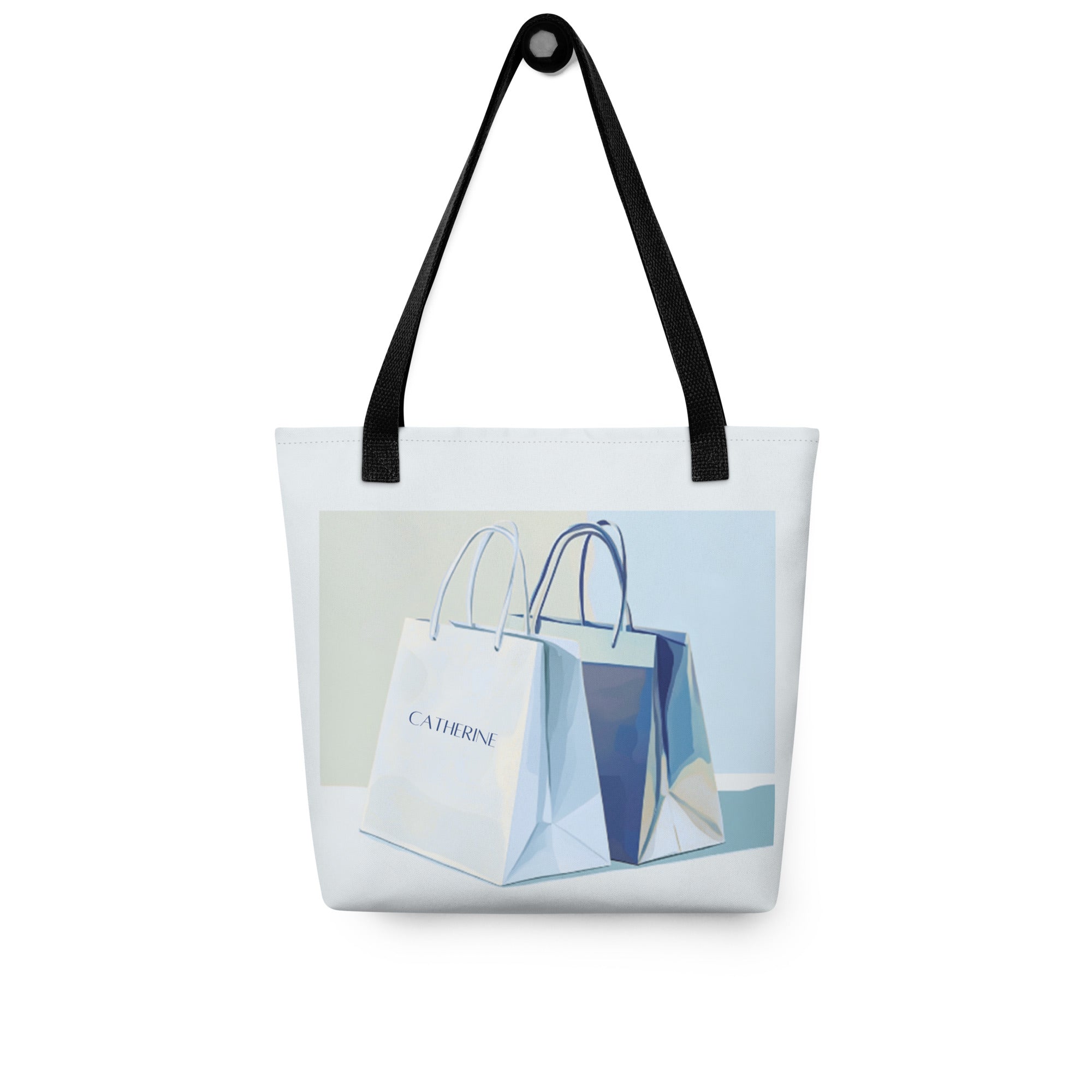 This blue tote bag with black handles features a unique graphic design. The front displays an illustration of two smaller tote bags, one of which can be personalised with a custom name. 