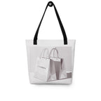This grey tote bag with black handles features a unique graphic design. The front displays an illustration of two smaller tote bags, one of which can be personalised with a custom name. 