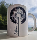 White glossy ceramic mug with a delicate black dandelion design and a custom name printed on the front. 11oz personalised coffee cup, ideal for tea, coffee, or hot chocolate lovers.